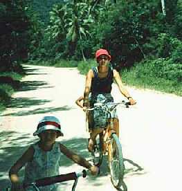 My wife and daughter on bicycles on a coral road.