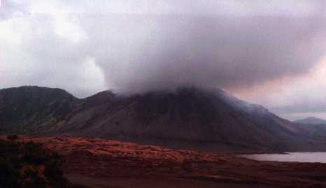 Volcano with peak obscured by volumns of smoke.